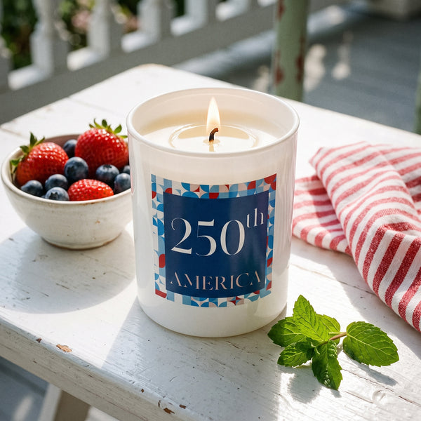 250th America Candle burning on a white-painted porch table in bright summer afternoon light | Noteology