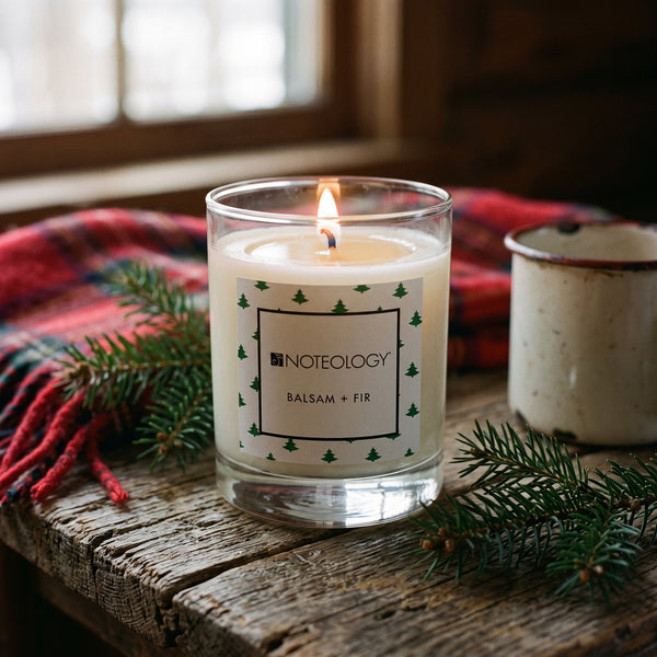 Balsam + Fir Candle burning on a log cabin side table in soft afternoon light | Noteology