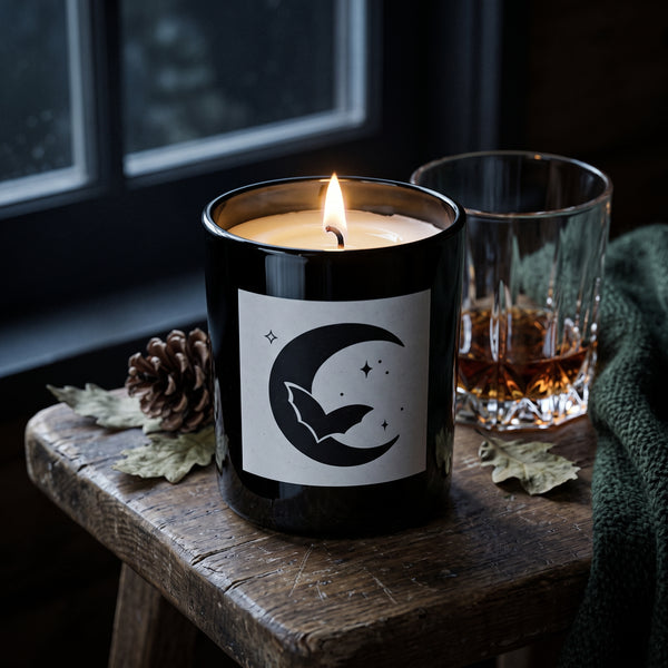 Crescent Moon Candle burning on a rough, weathered wooden stool beside a dark cabin window at night | Noteology