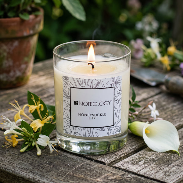 Honeysuckle Lily Candle burning on an outdoor garden table in dappled late afternoon shade | Noteology