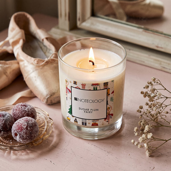 Sugar Plum Fairy Candle burning on a pale pink dressing table in soft winter light | Noteology