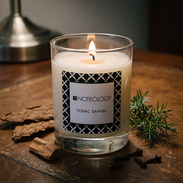 Tobac Santal Candle burning on a dark wooden table in a dim study | Noteology