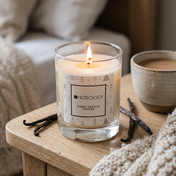 Warm Vanilla Winter Candle burning on a pale oak bedside table in soft winter morning light | Noteology