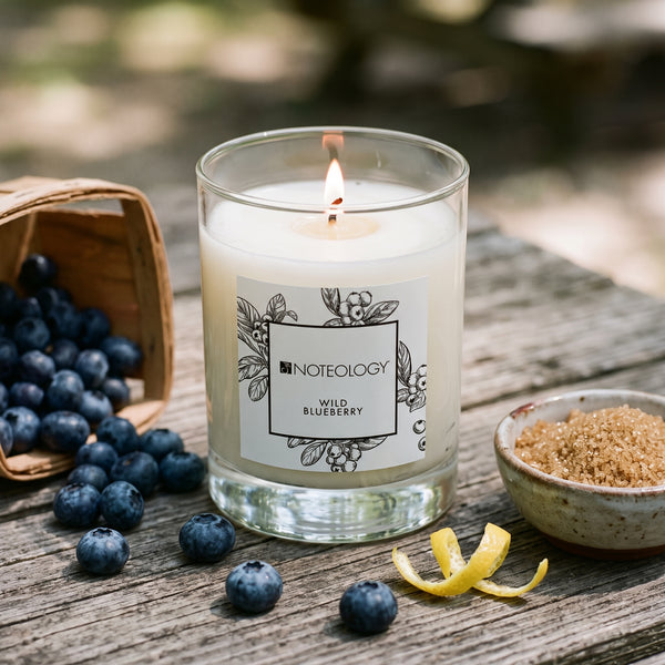 Wild Blueberry Candle burning on a rustic picnic table in summer shade | Noteology